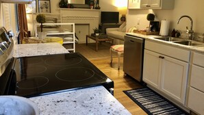A compact kitchen with a stove, dishwasher, and sink. There is a dining area with a table and chairs, and a living room with a sofa and a fireplace. - Convenient quiet LSU Location near City Park, coffee shops, restaurants and bars (Baton Rouge)