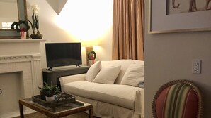 A living room with a sofa, a chair, a television, a fireplace, and a framed picture on the wall. - Convenient quiet LSU Location near City Park, coffee shops, restaurants and bars (Baton Rouge)