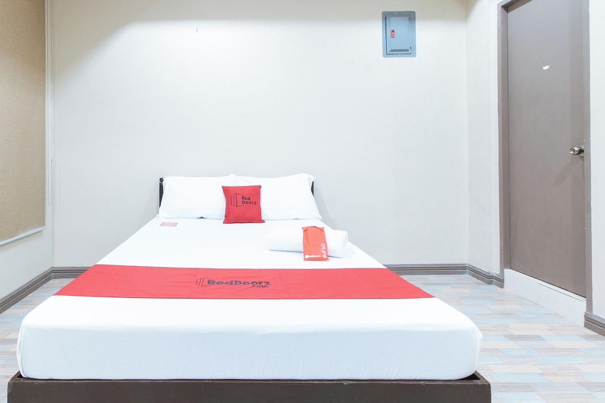 A single bed with a white mattress, a red blanket, and a red pillow with 'Red Doorz' branding.