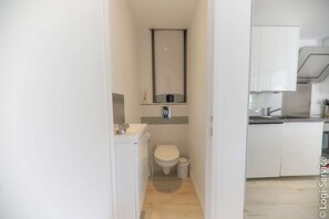 A compact bathroom with a toilet, sink, and mirror. - 1 bedroom apartment with garden (PORT GRIMAUD)