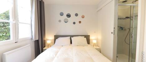 Un dormitorio con cama, ventilador de techo, ducha y una pared con espejos circulares.