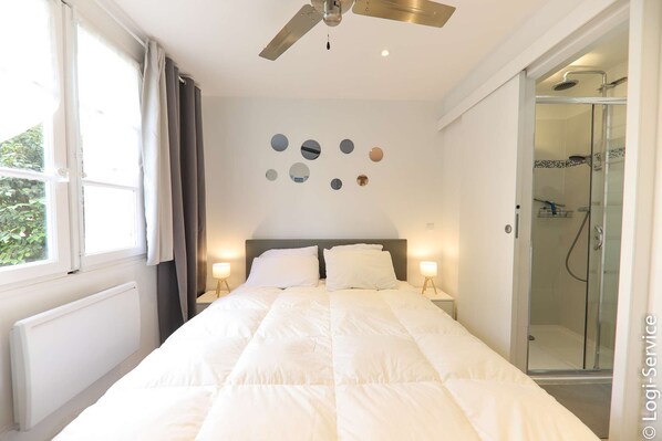 Un dormitorio con cama, ventilador de techo, ducha y una pared con espejos circulares.
