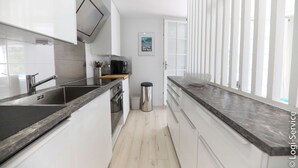 Une cuisine moderne avec des armoires blanches, un plan de travail noir et un évier en acier inoxydable.