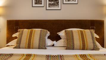 Cama com duas almofadas estampadas e um cobre-leito combinando, apoiada em uma cabeceira marrom.