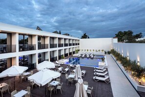A rooftop pool area with lounge chairs and tables, surrounded by a white building with balconies. - Évora O Cante Hotel (Évora)