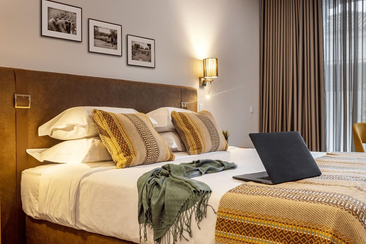 Ein Hotelzimmer mit einem Bett, einem Laptop und drei gerahmten Bildern an der Wand.