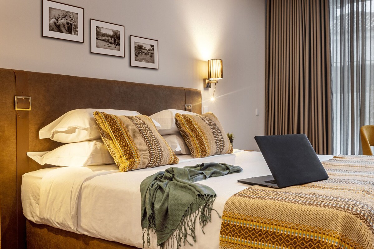 A hotel room with a bed, a laptop, and three framed pictures on the wall.