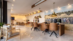 Een moderne woonkamer met een groot schilderij, een eetgedeelte met een houten tafel en stoelen, en een zithoek met een bank en salontafel.