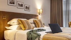 A hotel room with a bed, a laptop, and three framed pictures on the wall. - Évora O Cante Hotel (Évora)