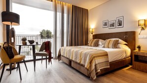 A hotel room with a large bed, a balcony with a table and chairs, and a view of the outdoors. - Évora O Cante Hotel (Évora)