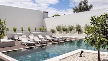 A pool area with lounge chairs and a clear view of the sea.