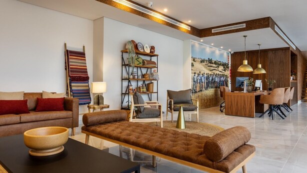 A modern living room with a sofa, armchairs, a coffee table, and a bookshelf. - Évora O Cante Hotel (Évora)