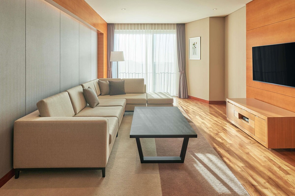 A modern living room with a sofa set, a coffee table, a flat-screen TV, and a wooden entertainment unit.