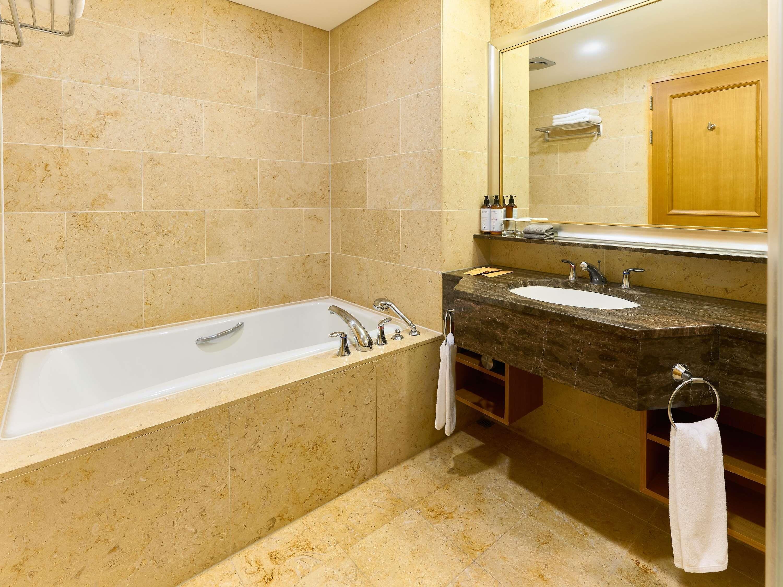 A bathroom with a bathtub, a sink, and a mirror.