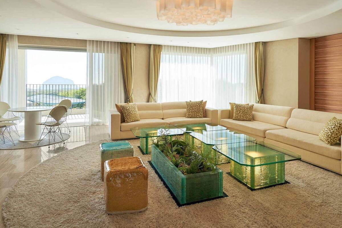 A modern living room with a sofa set, glass coffee table, and decorative planters.