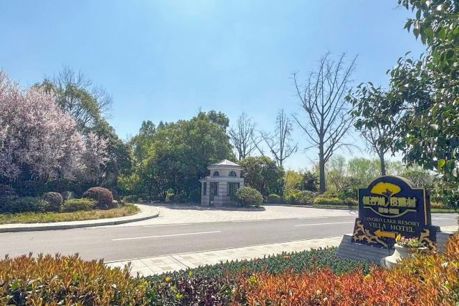 A sign for Dongro Lake Resort Villa Hotel with a clear view of the entrance and surrounding greenery.