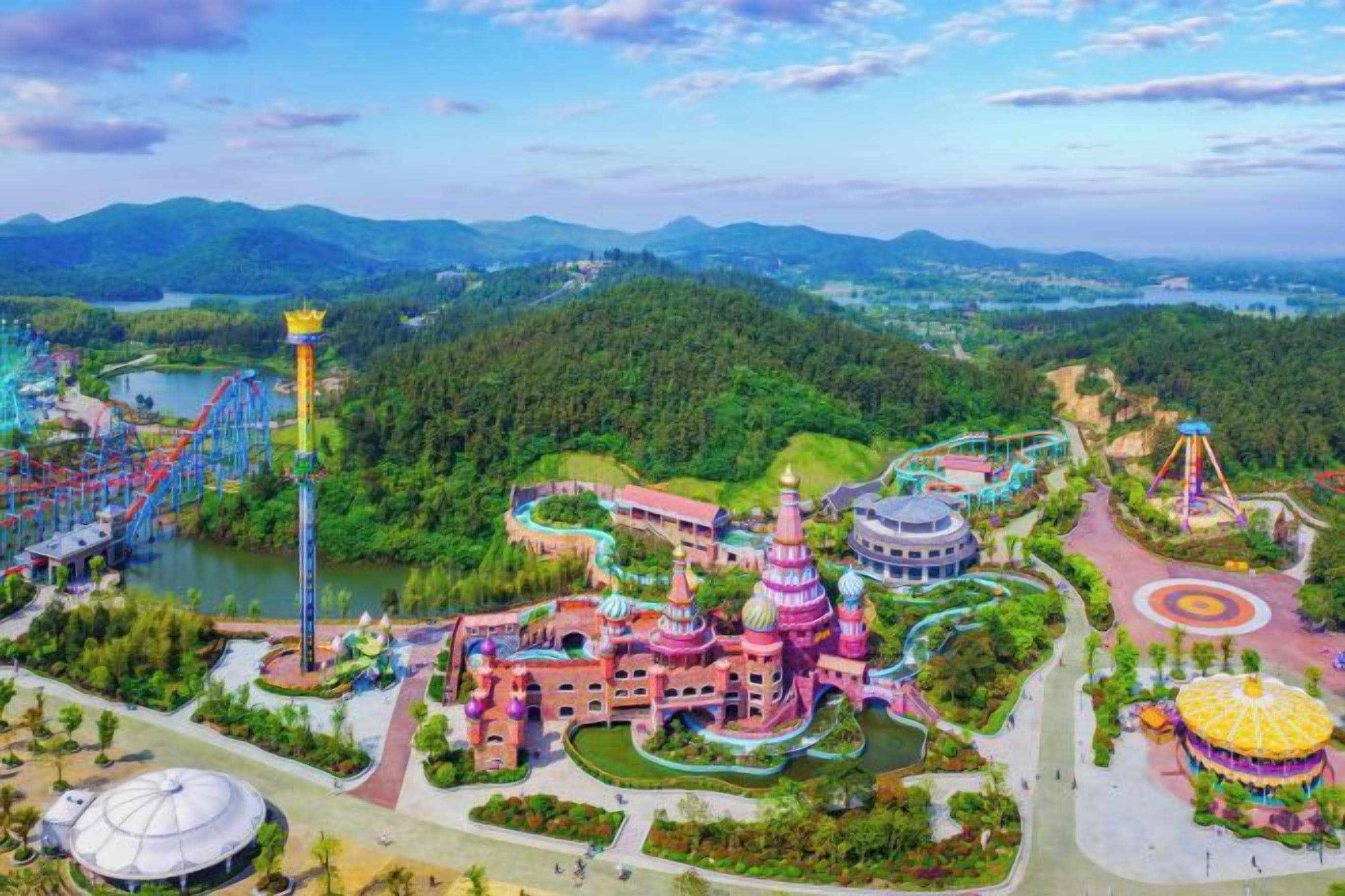 A theme park with roller coasters, a large building with a dome, and a lake.