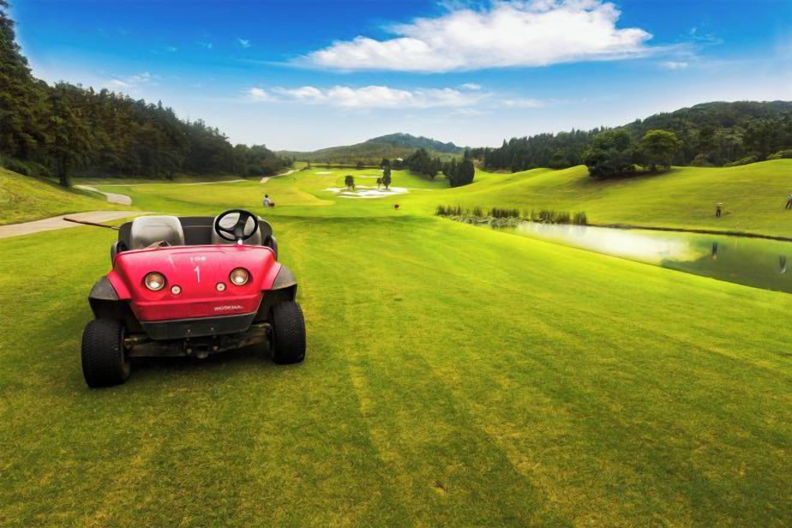 A golf cart on a well-manicured golf course with a pond and trees in the background.