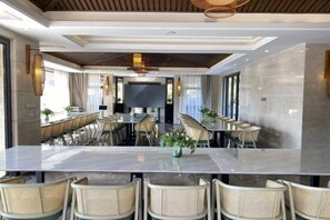 A modern hotel dining area with a long table, multiple chairs, and a television screen. - Gingko Lake Resort Hotel Villa (Nanjing)