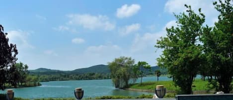 Una piscina con vistas a un lago y colinas, rodeada de vegetación.