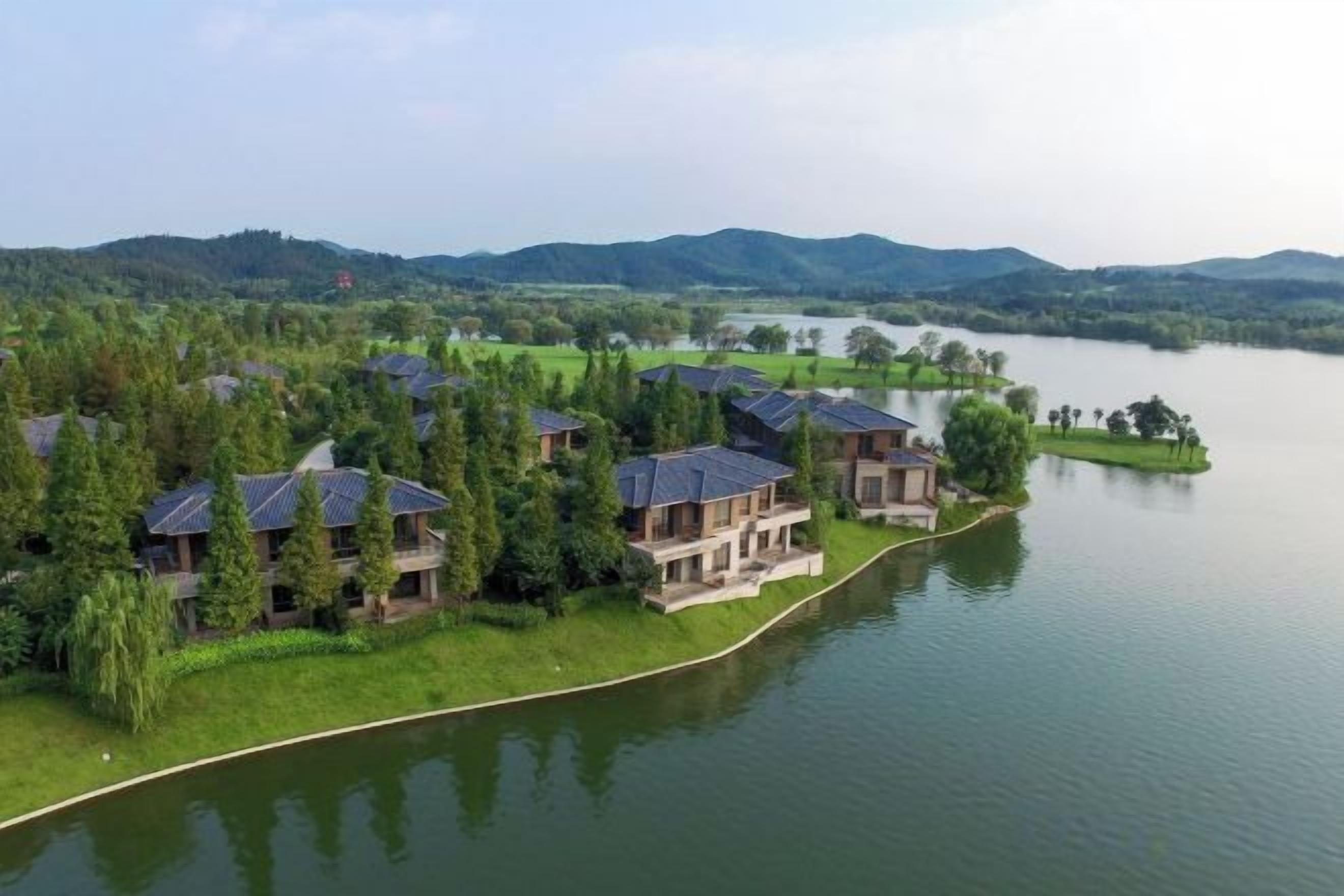 A lakeside property with multiple buildings, a river, and surrounding greenery.