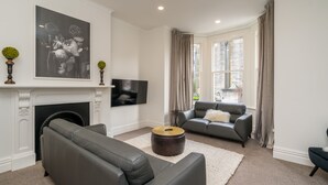 A modern living room with a fireplace, a flat-screen TV, and two leather sofas. - Inner City Elegance on Stuart Street (Dunedin)