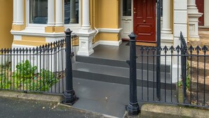 A two-story building with a yellow facade, white trim, and a red door. - Inner City Elegance on Stuart Street (Dunedin)