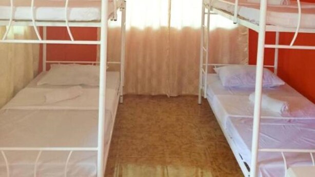 A room with bunk beds, a ceiling fan, and a window with curtains. - Reddoorz @ Garcia Hernandez Bohol (Garcia Hernandez)