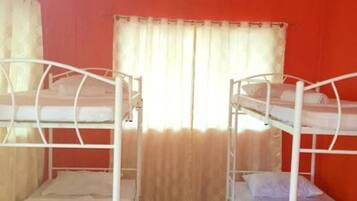 A room with bunk beds, a ceiling fan, and a window with curtains.