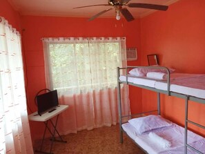 Une chambre de dortoir avec des lits superposés, un bureau avec un ordinateur et une fenêtre avec des rideaux.