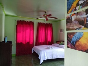 Un dormitorio con cama, cortinas rojas, ventilador de techo y una pared decorada con imágenes de pájaros.