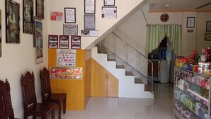 A reception area with a staircase, framed certificates, and a display of products. - Reddoorz @ Garcia Hernandez Bohol (Garcia Hernandez)