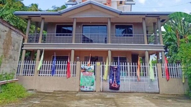 Un edificio de dos pisos con techo plano y entrada central.