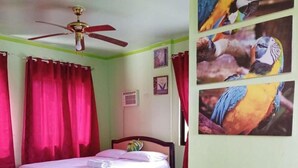 A bedroom with a bed, a ceiling fan, red curtains, and three parrot pictures on the wall. - Reddoorz @ Garcia Hernandez Bohol (Garcia Hernandez)