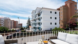 Een balkon met witte rieten meubels, een fruitschaal en een vaas met bloemen.