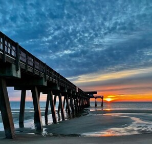 Un muelle que se adentra en el agua, con un atardecer de fondo.