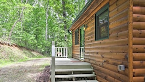 A wooden cabin with a porch and steps leading to a door.