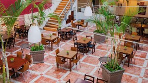 A spacious indoor dining area with multiple tables and chairs, potted plants, and a staircase. - Sunset Palace Beach Hotel (Mazatlán)