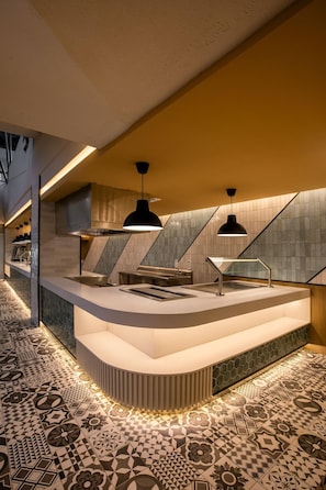 A modern kitchen with a curved countertop, pendant lighting, and patterned tile flooring.
