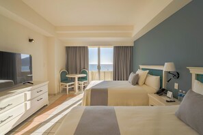 Habitació d'hotel amb llit, escriptori, cadira, televisió i vista a l'oceà.