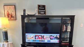A living room with a flat-screen TV, a coffee table, a bookshelf, and a lamp. - whole 3 bedroom home (Eagle Pass)