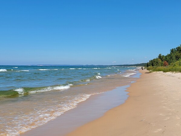 Une plage avec une eau d’un bleu limpide, un rivage sablonneux et une végétation luxuriante le long de la côte.