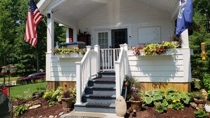 Un bâtiment blanc doté d’un porche, d’un escalier et de jardinières.