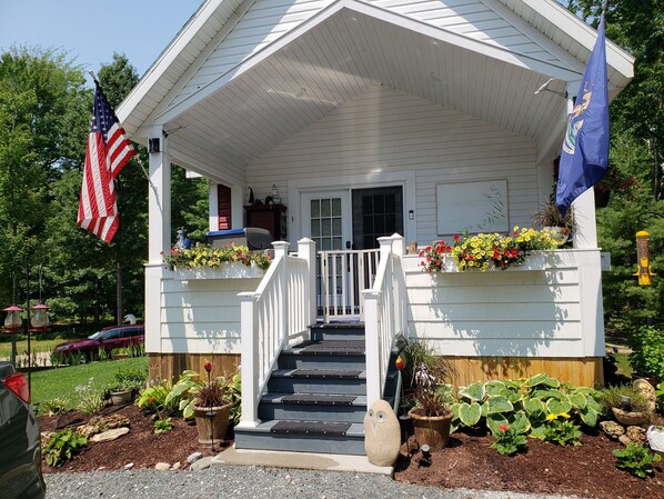 A white building with a porch, steps, and flower boxes.
