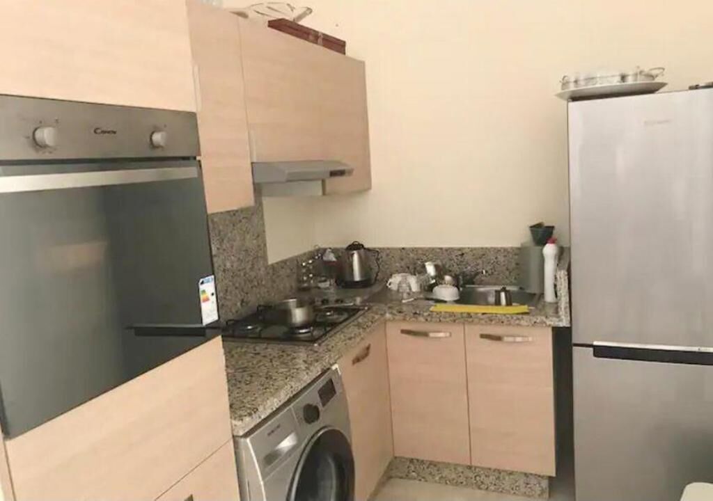 A compact kitchen with a built-in oven, a washing machine, and a refrigerator.