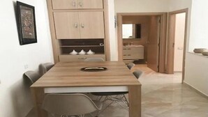 Een knus woongedeelte met een eettafel, stoelen, een inbouwkast en een kleine kitchenette.