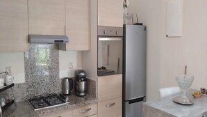 Una cocina moderna con estufa a gas, electrodomésticos de acero inoxidable y encimera de mármol.