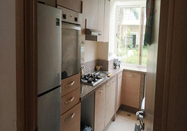 A kitchen with a refrigerator, stove, and sink.
