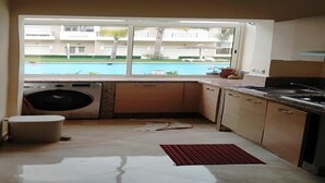 Une cuisine compacte équipée d’un lave-linge, d’un évier et d’une fenêtre donnant sur une piscine.