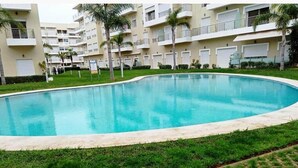 Una piscina circondata da un prato e un vialetto lastricato.